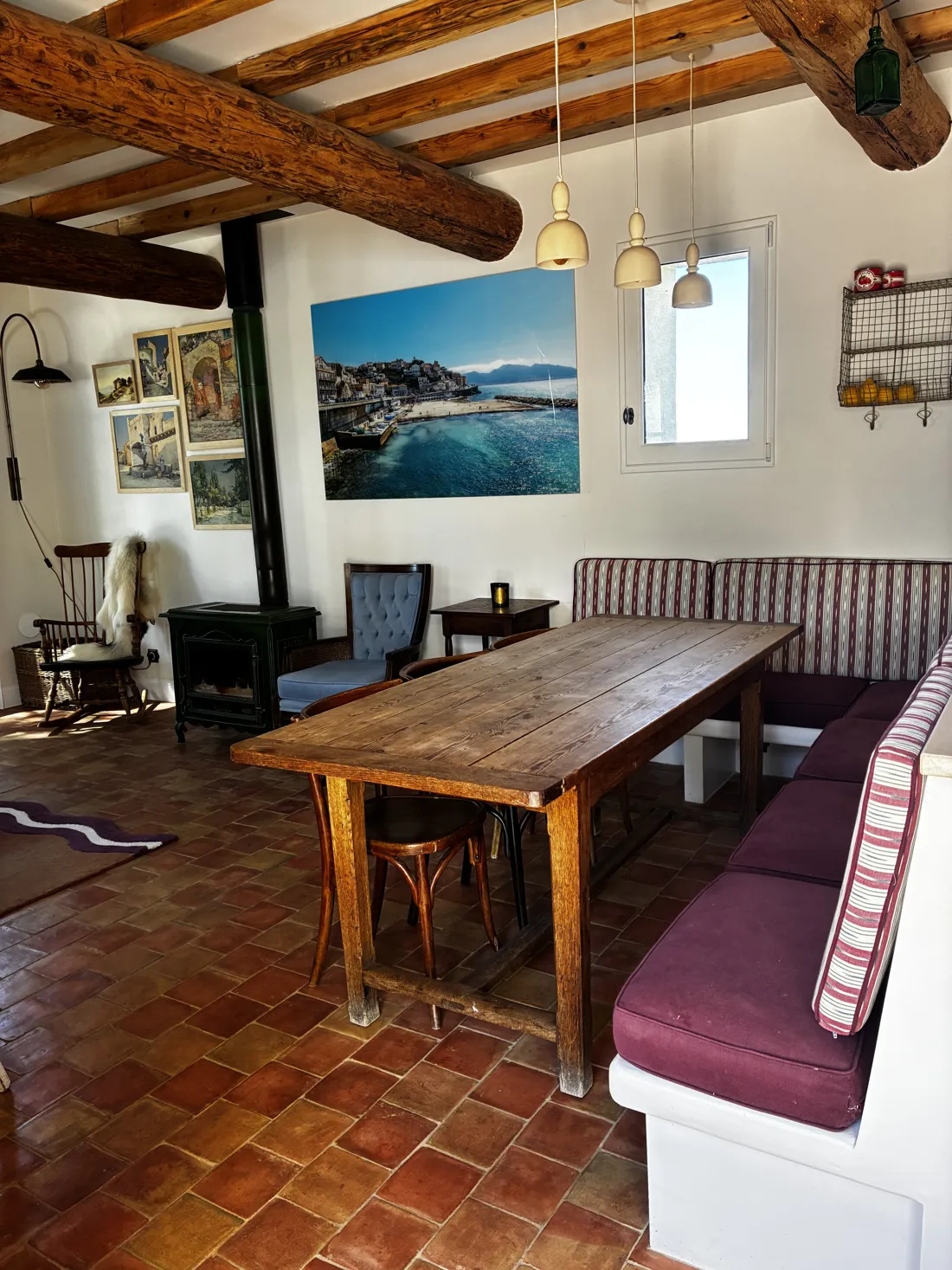 Grande table en bois sous les poutres, banquette et tomettes : la pièce de vie d'un mas rénové au pied du Ventoux
